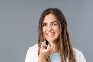 Smiling Female Patient Holding Invisalign