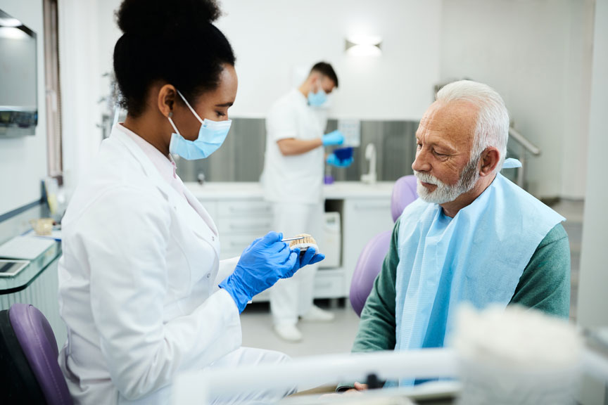Dentist Showing Dentures To Patient